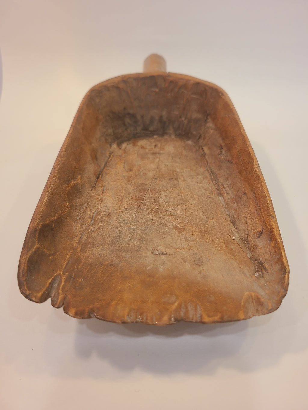 Front view of antique hand-carved hardwood grain scoop showing honey-brown patina and naturally worn scalloped rim
