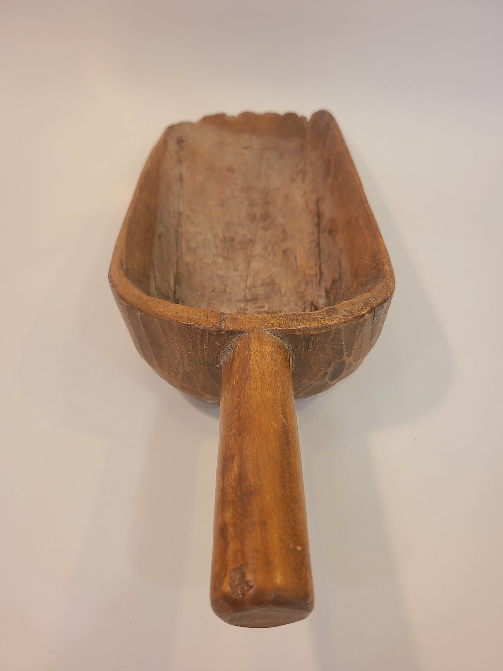 Three-quarter view of late 19th century hand-carved hardwood grain scoop with aged honey-brown patina — primitive folk art