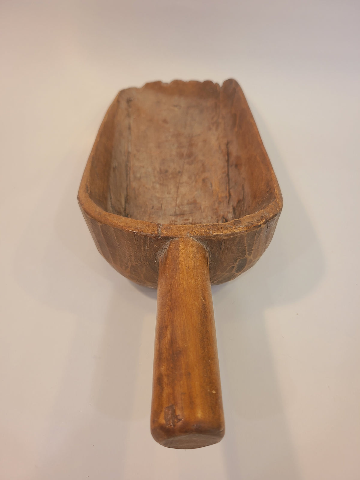 Three-quarter view of late 19th century hand-carved hardwood grain scoop with aged honey-brown patina — primitive folk art