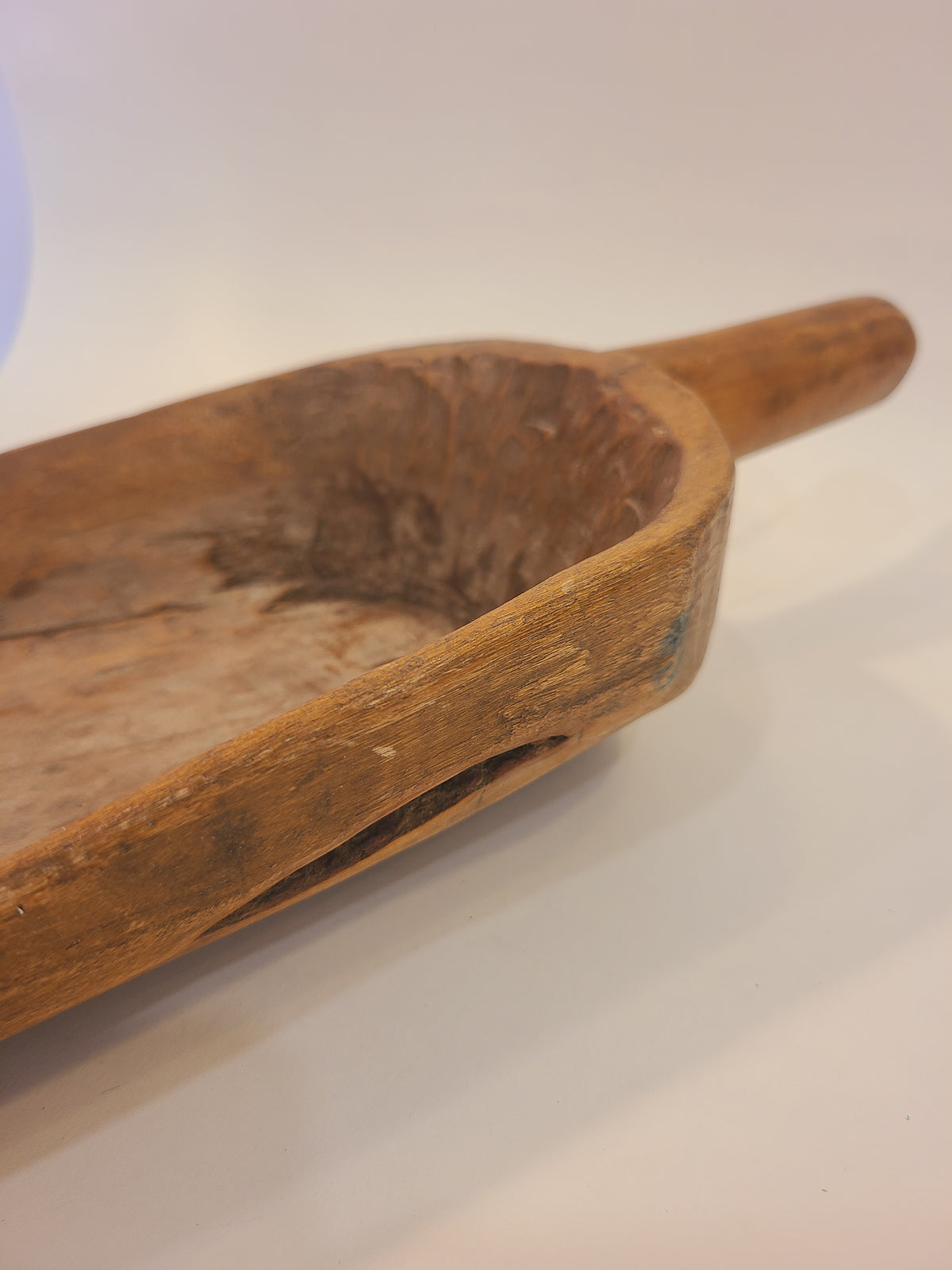 Side profile of antique hand-carved hardwood grain scoop showing honey-brown patin