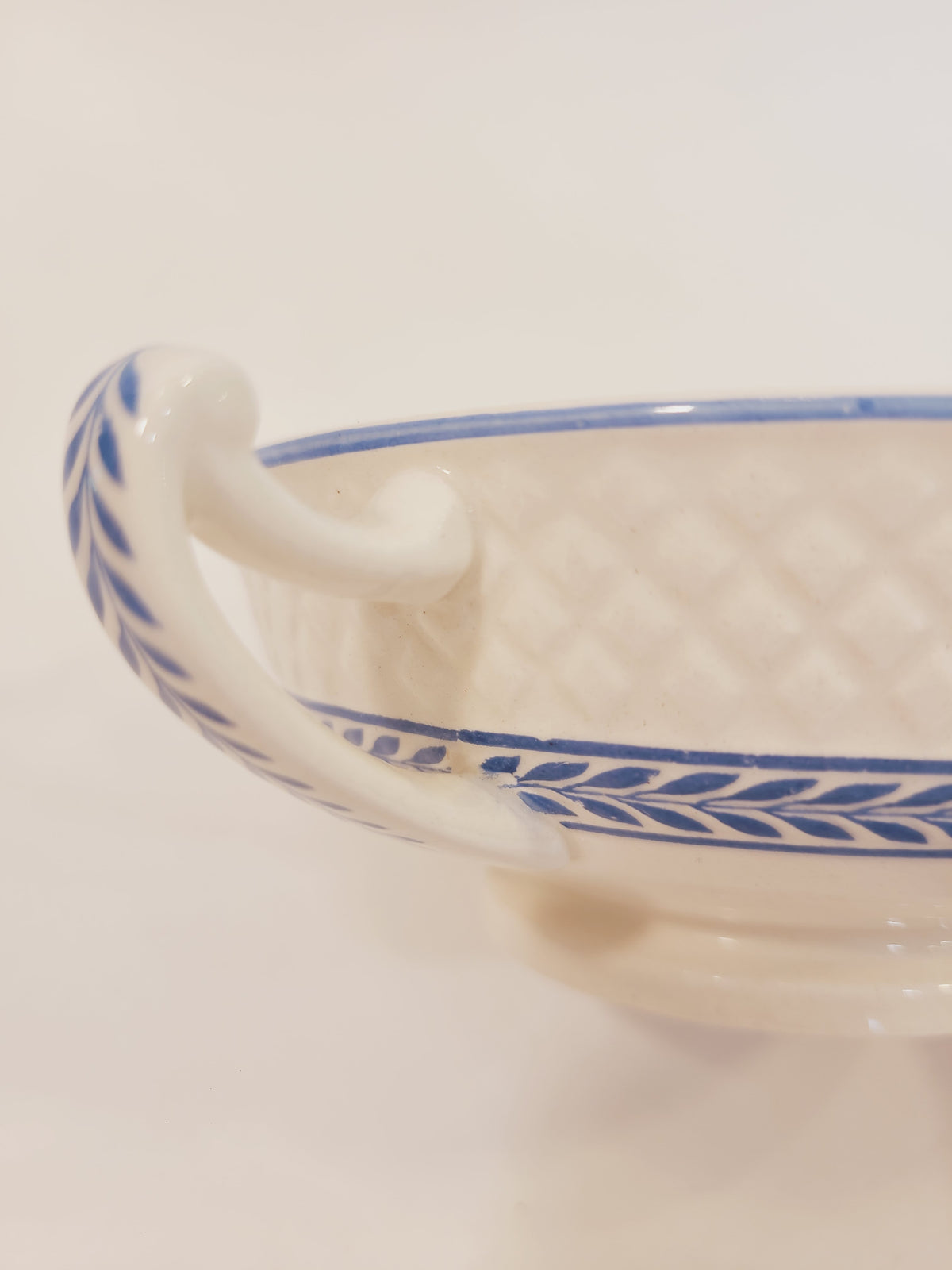 Close-up of Copeland Spode Elaine Mansard cream soup bowl handle showing soft blue laurel vine and embossed diamond texture
