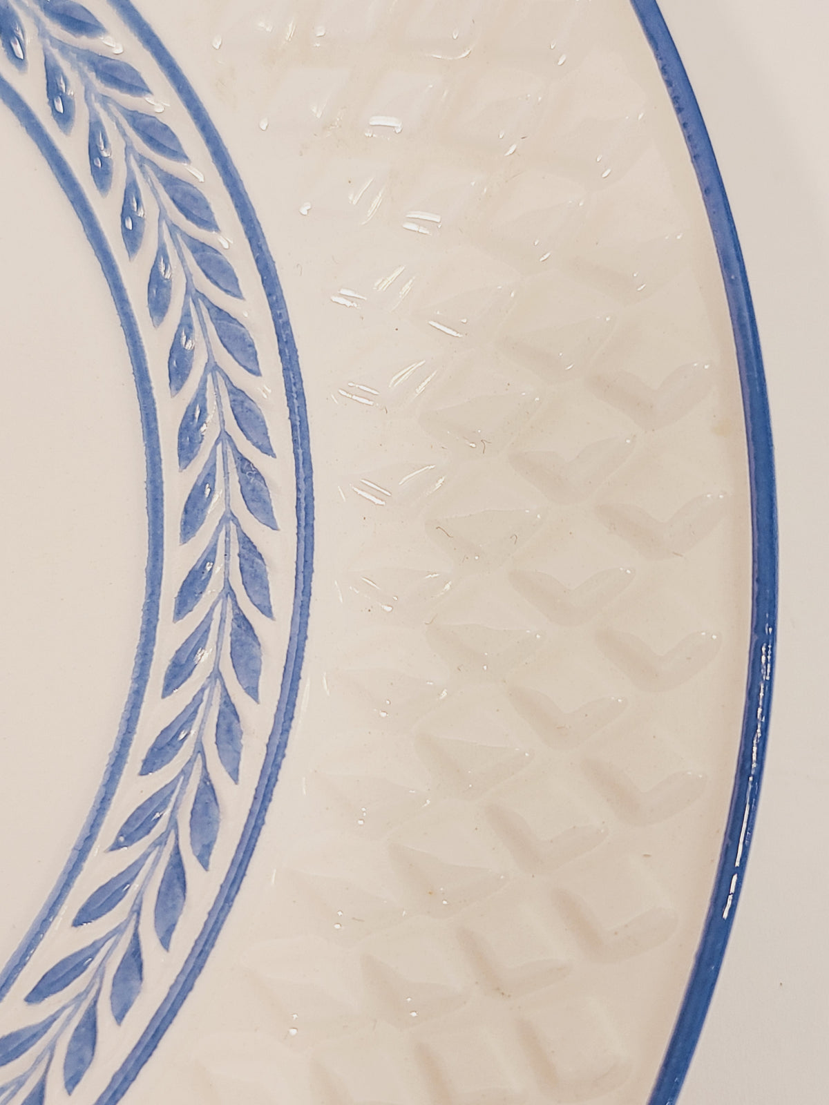 Macro close-up of Copeland Spode Elaine soft blue laurel vine pattern and embossed Mansard diamond rim on ivory creamware
