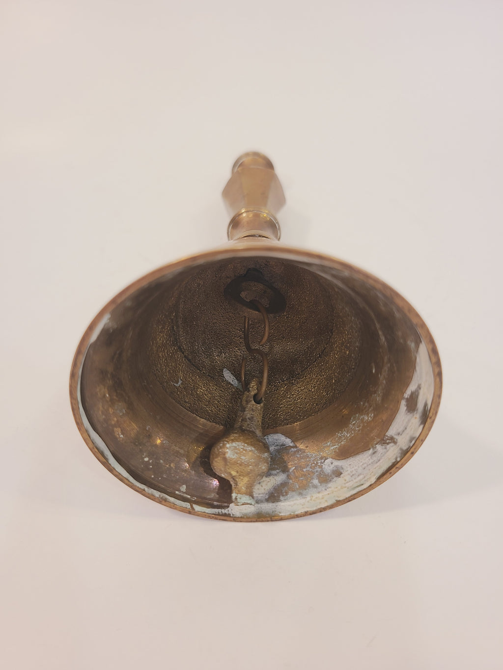 Interior view of vintage solid red brass hand bell showing original intact metallic clapper and aged patina