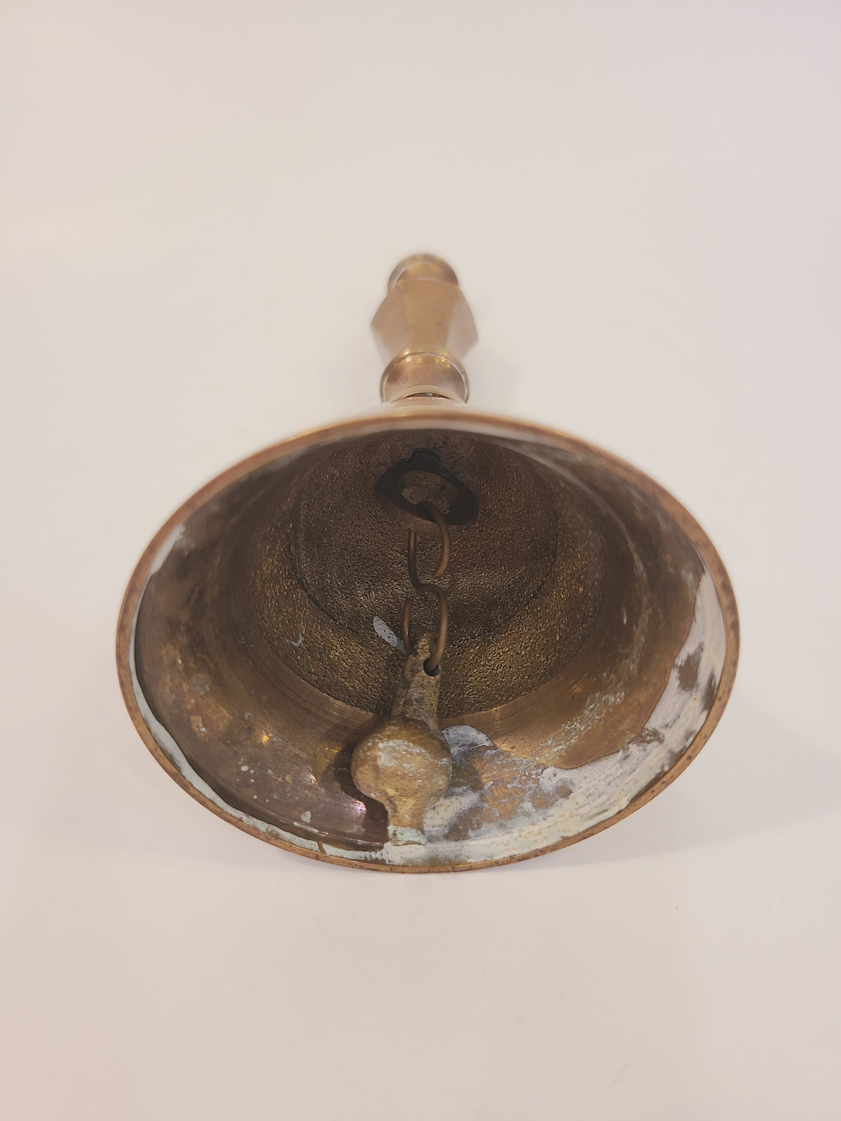 Interior view of vintage solid red brass hand bell showing original intact metallic clapper and aged patina