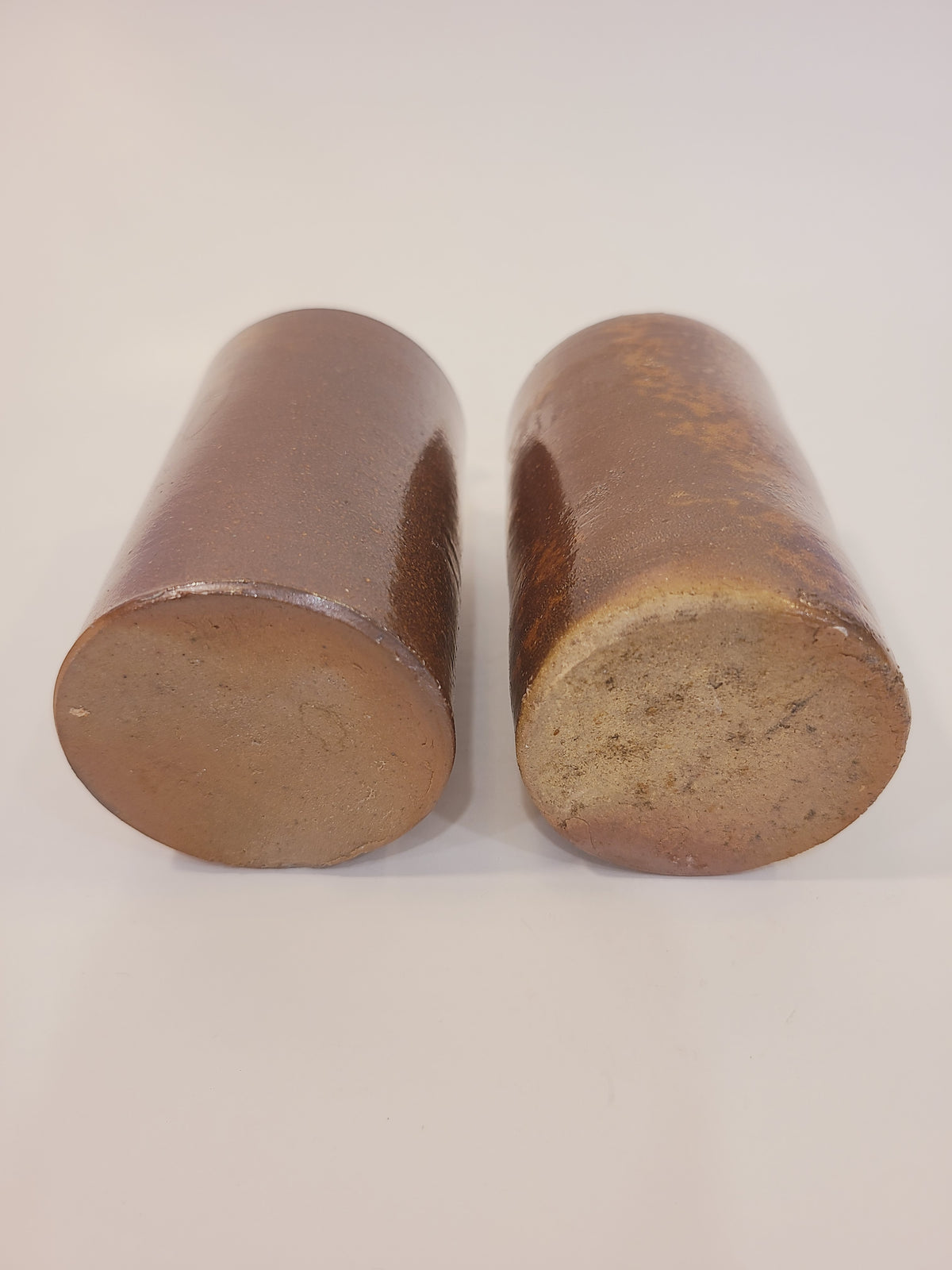 Close-up of bottoms of antique salt-glazed stoneware ink bottle showing rustic kiln-fired orange peel glaze texture
