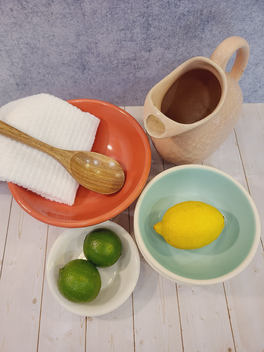 Mid-century coral glaze utility bowl styled in kitchen vignette with wooden spoon, linen, citrus, and stoneware pitcher