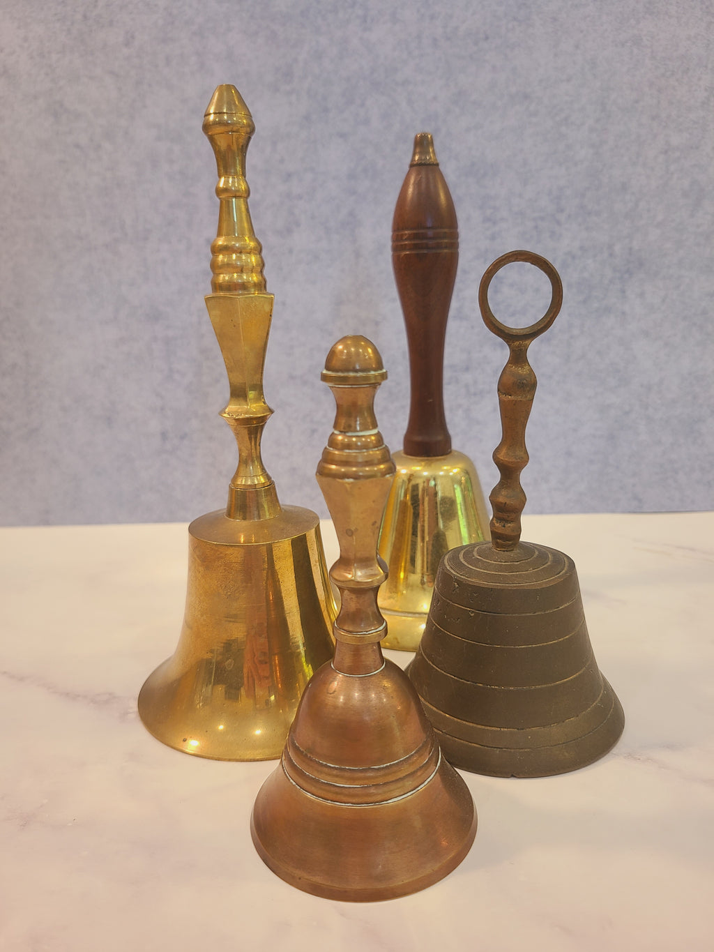 Vintage solid red brass hand bell shown with collection of antique brass and wood-handled bells — size and style comparison