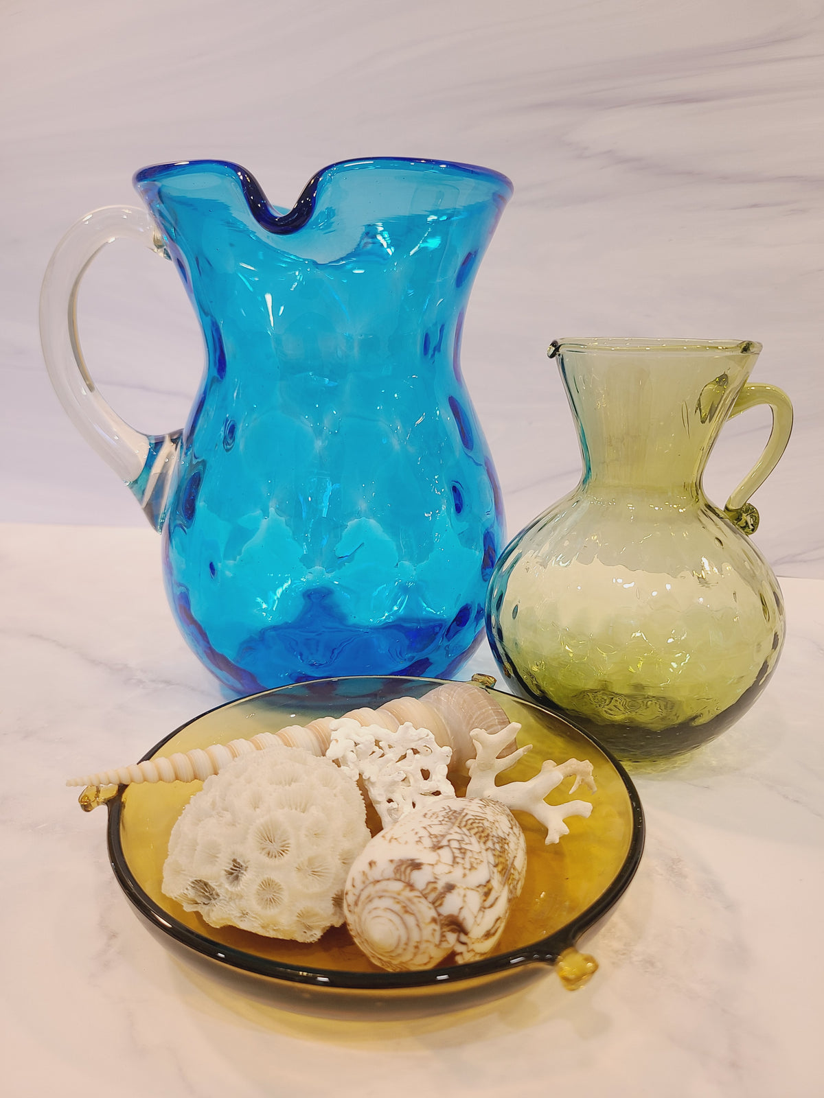 Petite olive green handblown optic glass pitcher displayed with turquoise glass pitcher and shells
