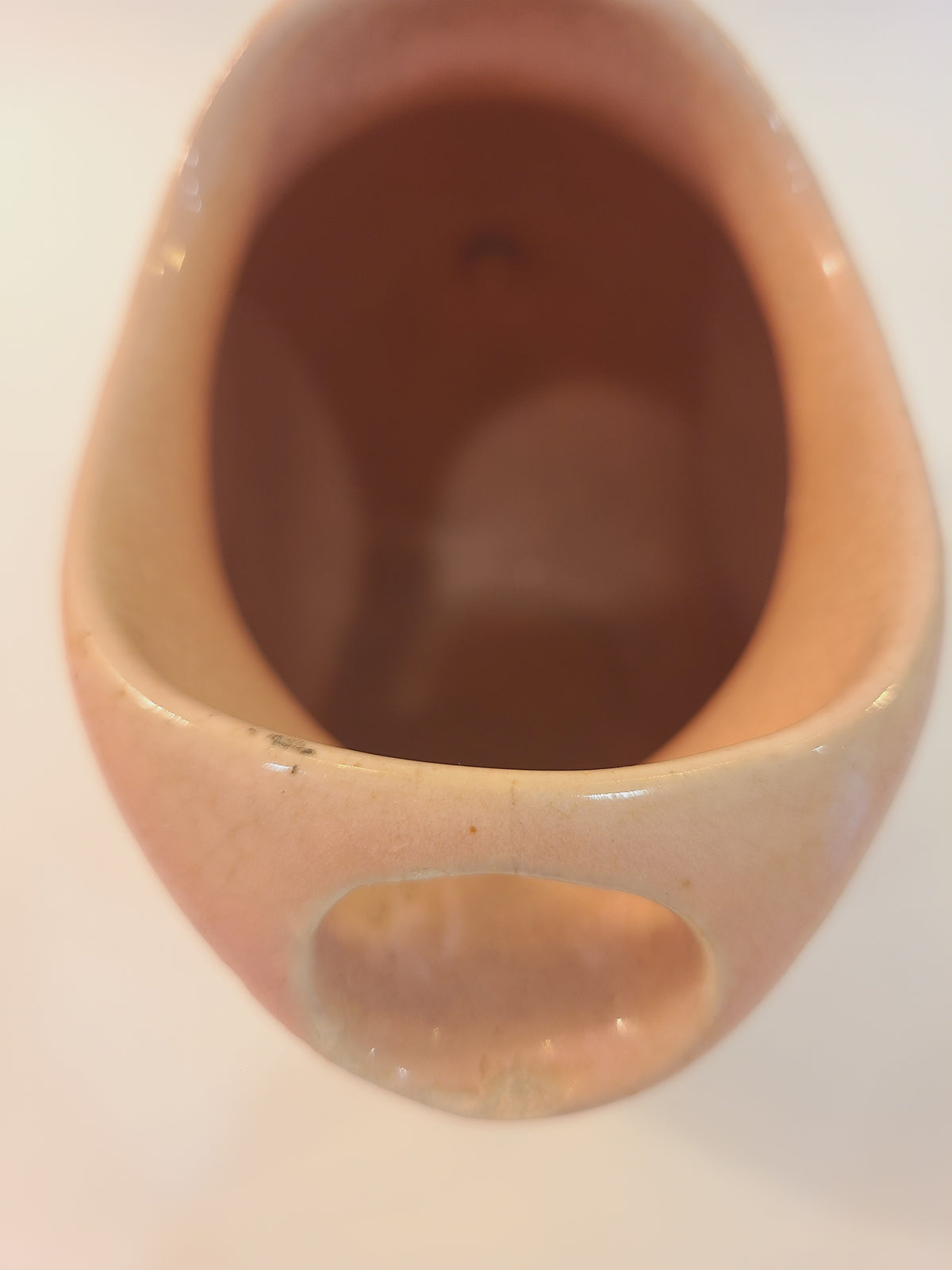 Top-down view inside Hull Pottery Nuline Bak-Serve pitcher showing built-in ice-catcher bar, blush pink ceramic glaze interior, 1937