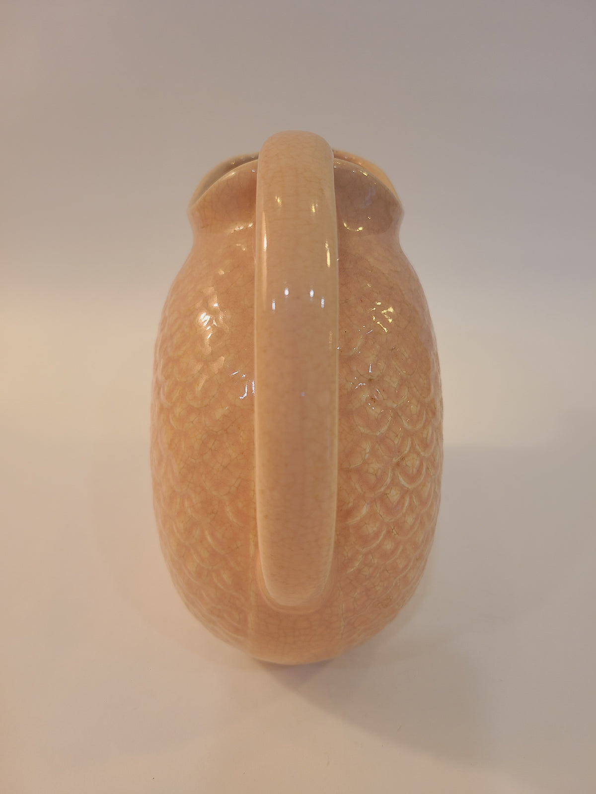 Rear handle view of Hull Pottery blush pink fish scale pitcher showing C-shaped handle and all-over embossed scale texture, Nuline Bak-Serve line