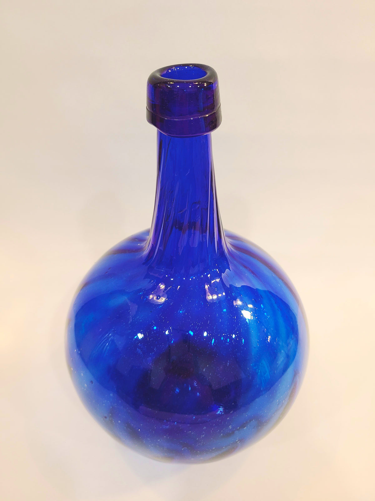Front view of a cobalt blue glass onion bottle showing swirled pattern