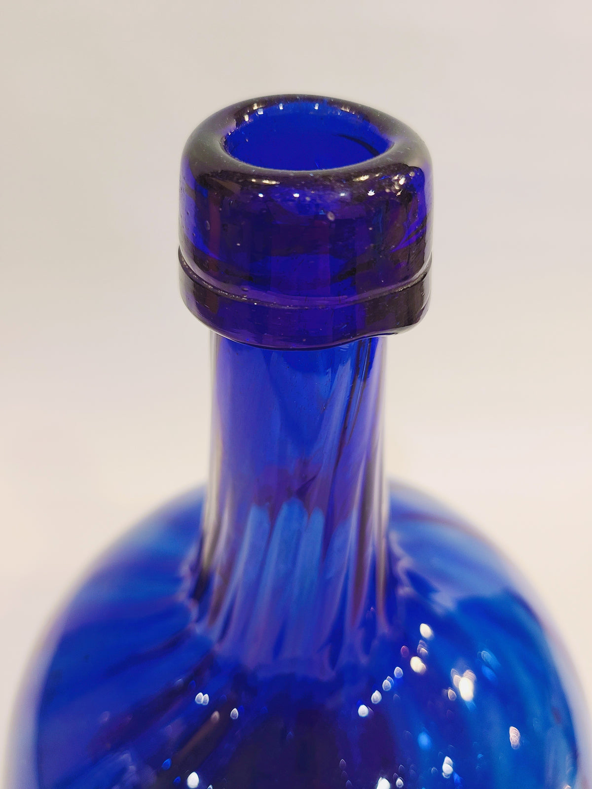 Close-up of the wide bottle opening and long neck on a hand-blown cobalt blue glass bottle
