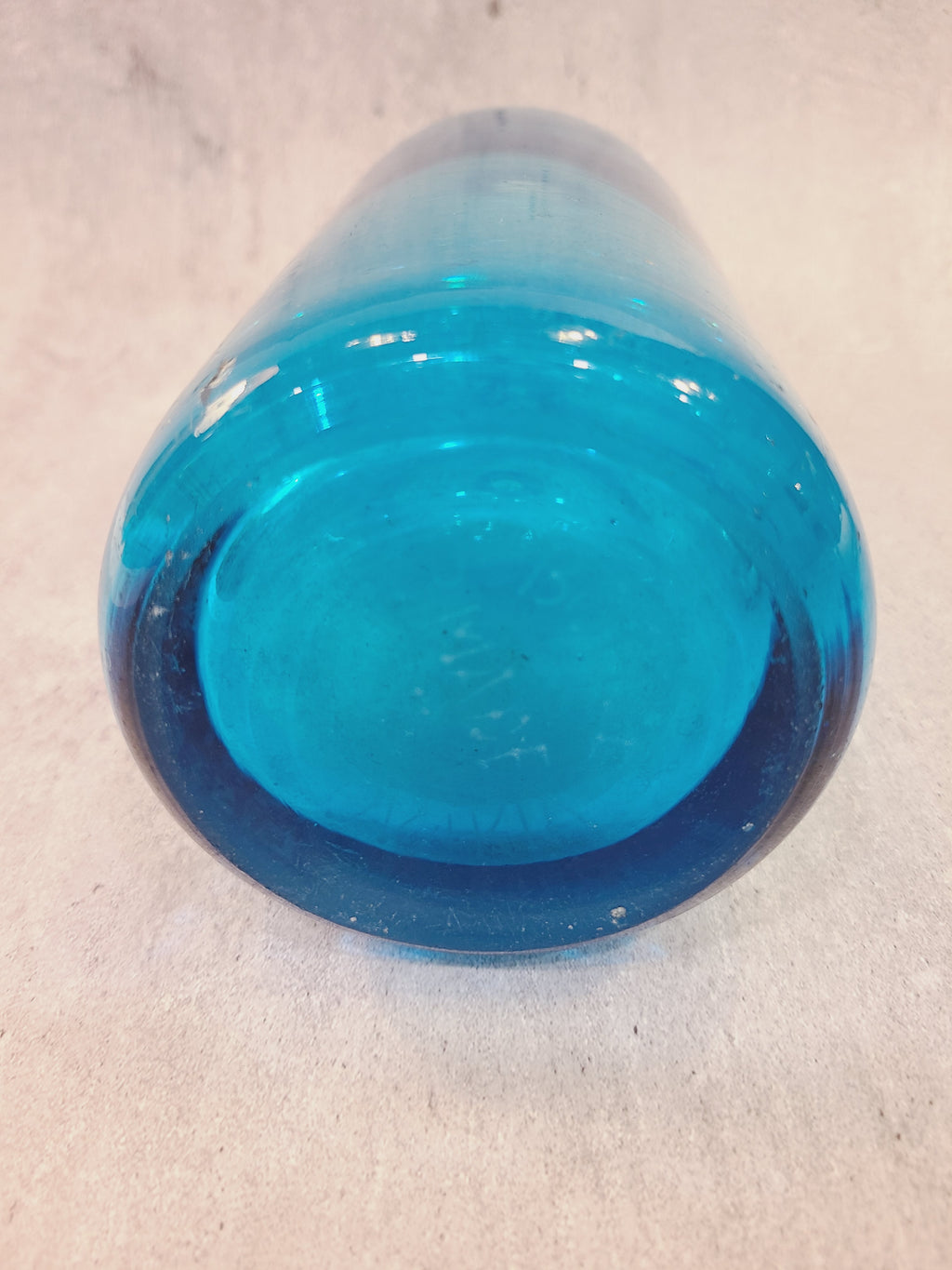 Bottom of a vintage turquoise Czechoslovakian seltzer bottle showing its thick glass base