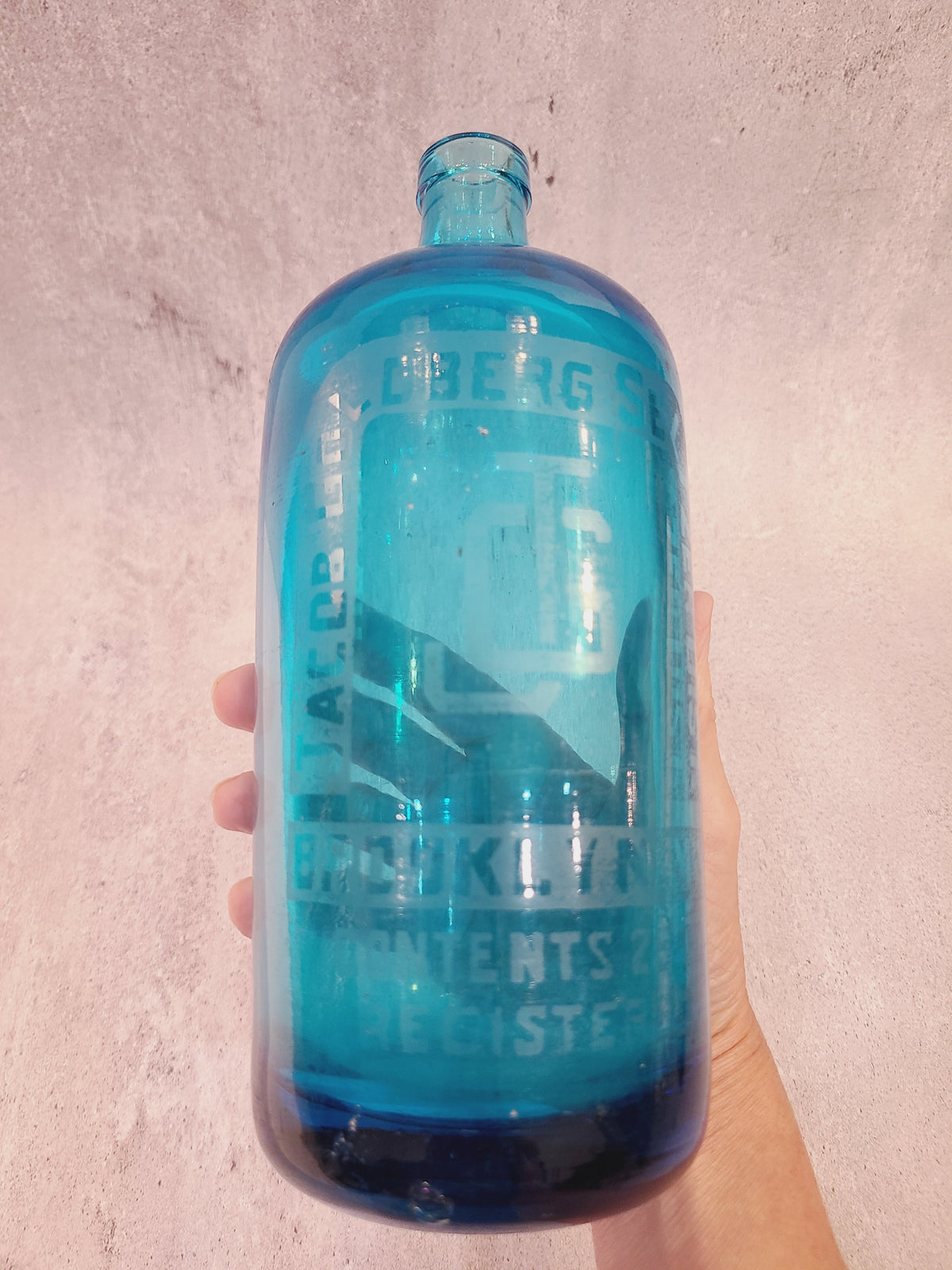 Turquoise seltzer bottle showing etched Brooklyn, New York lettering