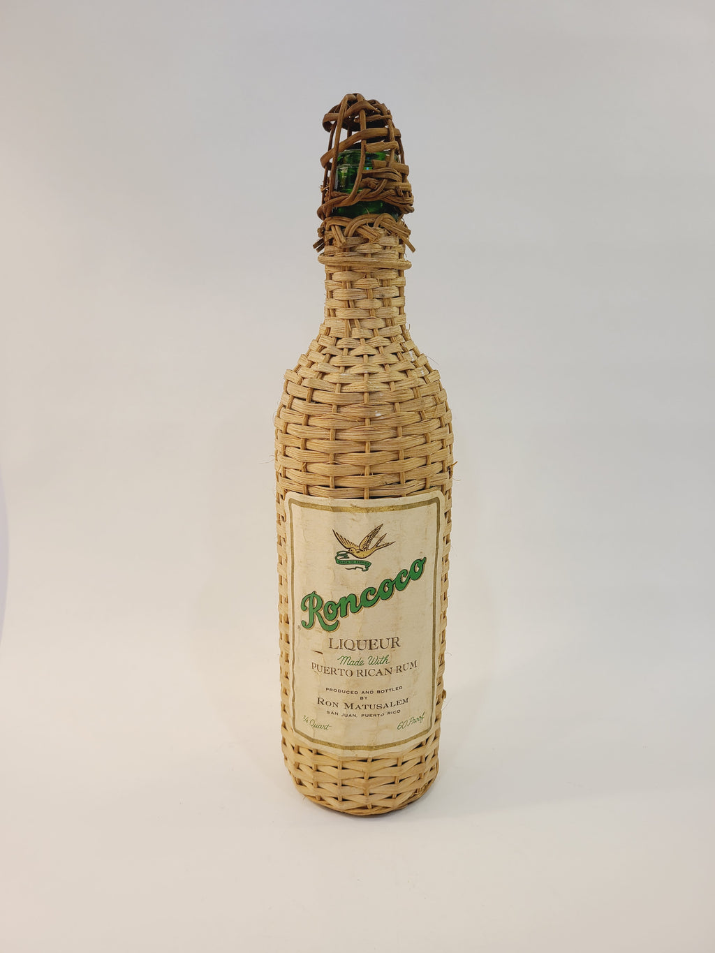 Roncoco Coconut Rum Liqueur wicker-wrapped bottle, front label, Ron Matusalem 1970s–80s coastal or tiki barware decor