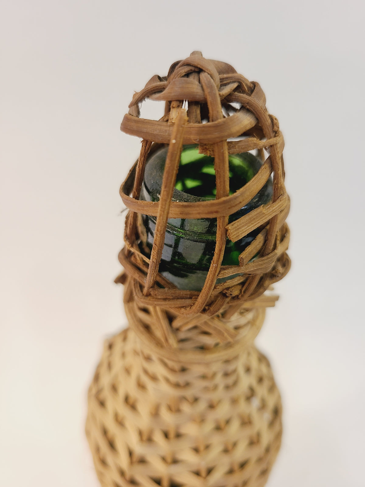 Close-up of wicker rattan top cap on Roncoco rum bottle showing original green glass bottle neck, vintage tiki decor
