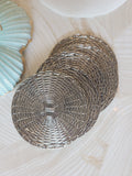 Set of 5 mid-century woven metal drink coasters stacked overhead view, polished silver basketweave, coastal tabletop styling
