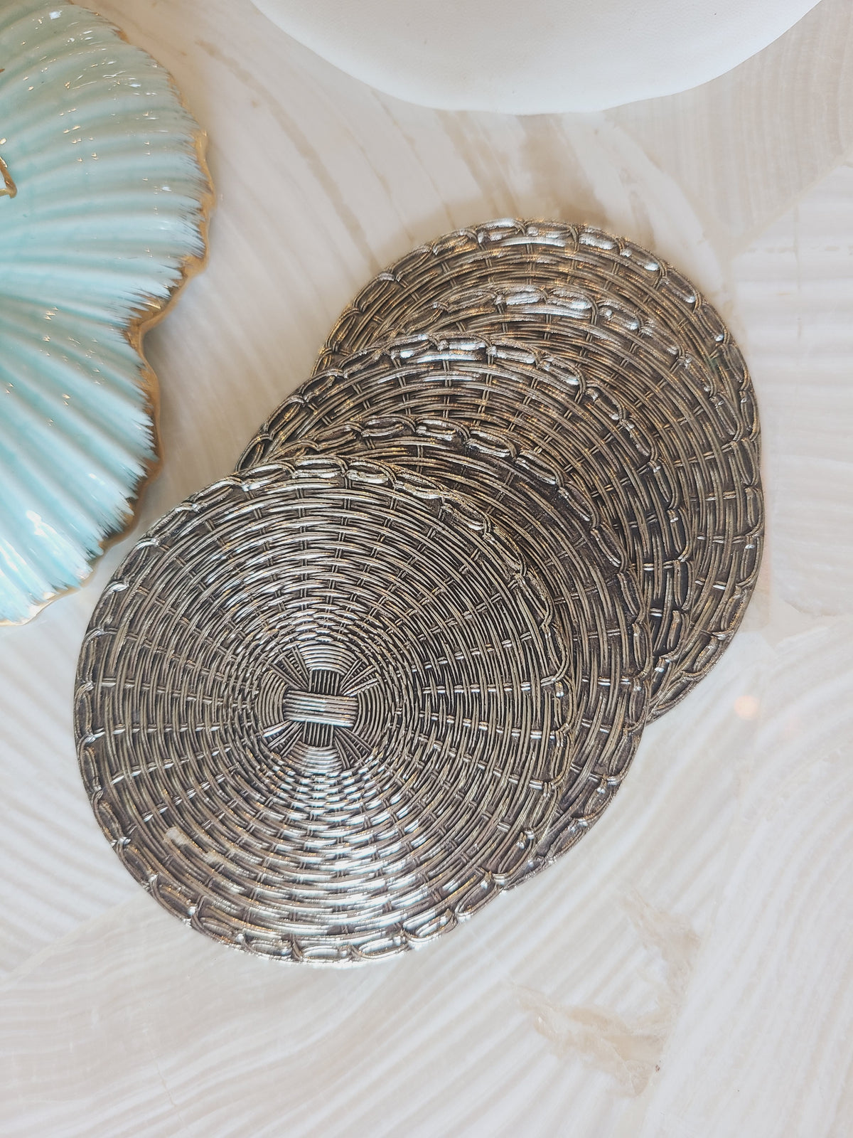 Set of 5 mid-century woven metal drink coasters stacked overhead view, polished silver basketweave, coastal tabletop styling