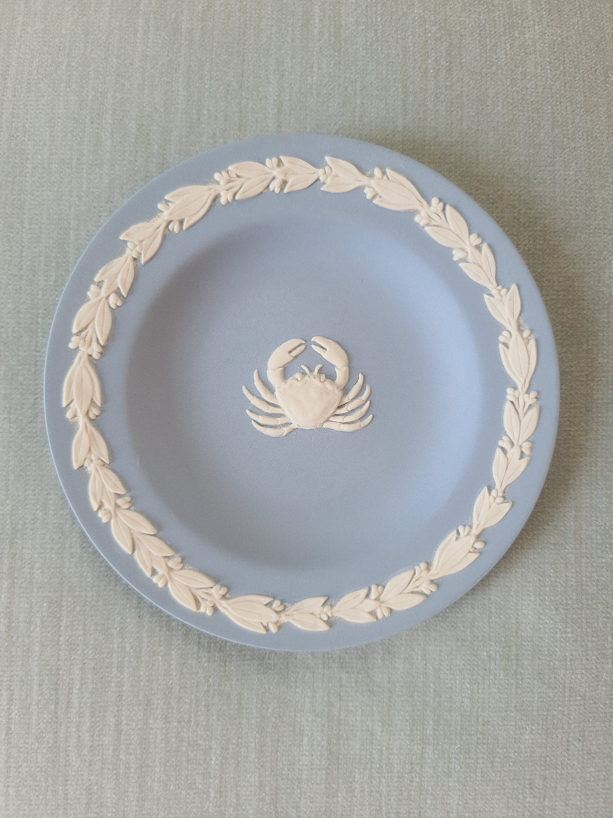 Wedgwood blue jasperware Cancer crab zodiac pin plate top view on linen, white bas-relief crab cameo centered with leaf garland border, Made in England