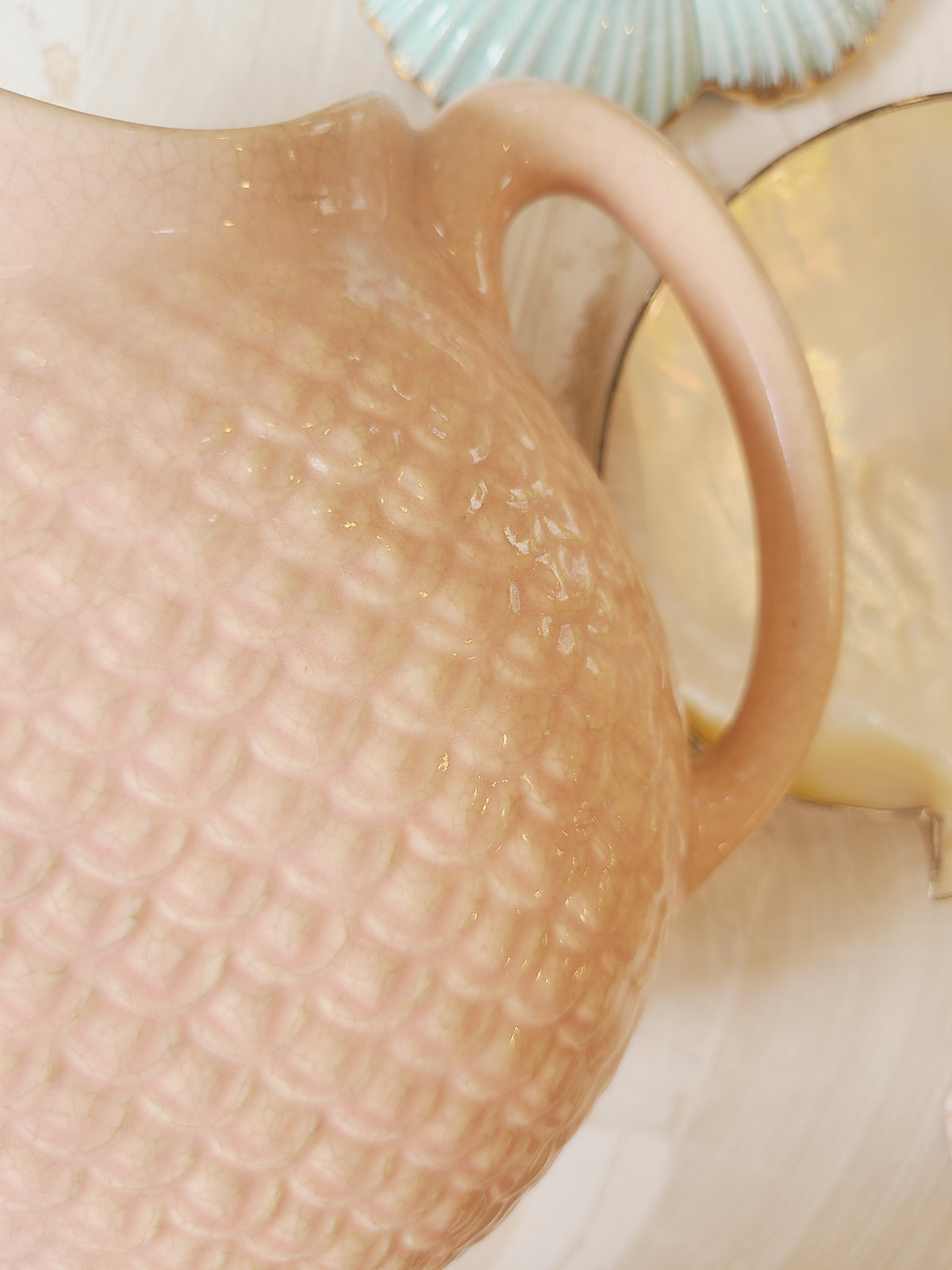 Macro close-up of Hull Pottery Nuline Bak-Serve fish scale embossed texture on blush pink ceramic, coastal styling