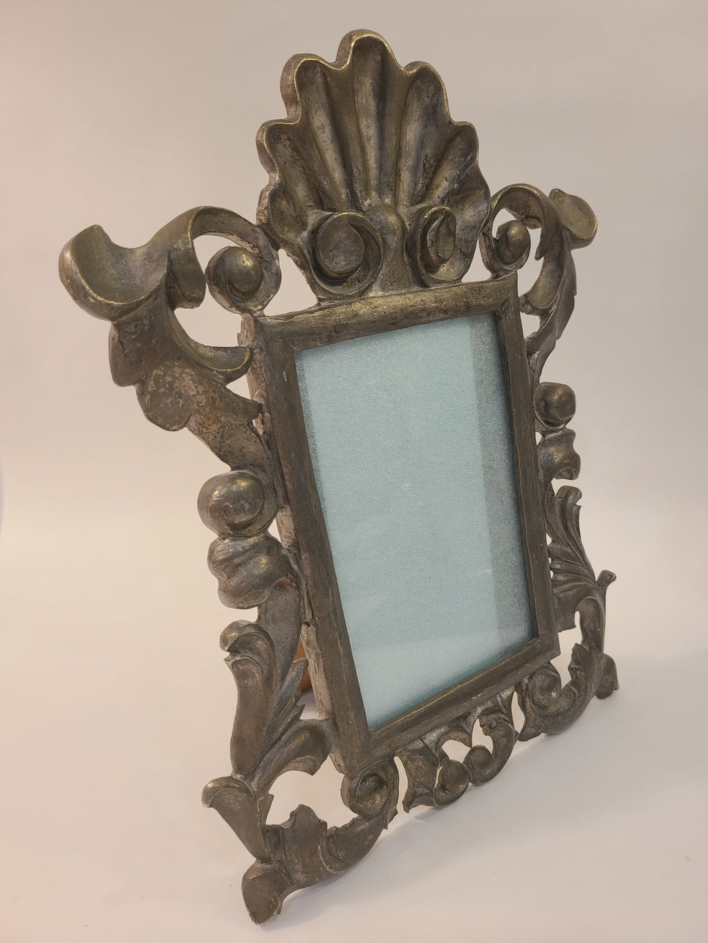 Angled side view of Rococo Revival cast alloy picture frame showing fold-out easel stand and openwork scrollwork, vintage coastal decor