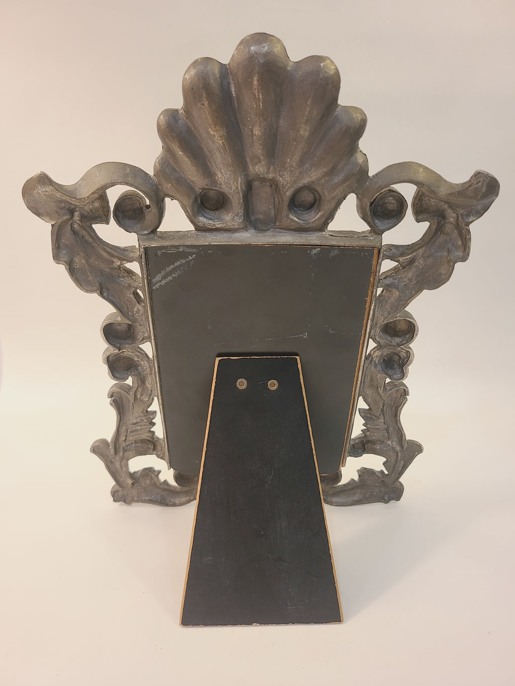 Back of Rococo Revival cast metal picture frame with fold-out easel stand extended, shell crest visible, vintage tabletop decor