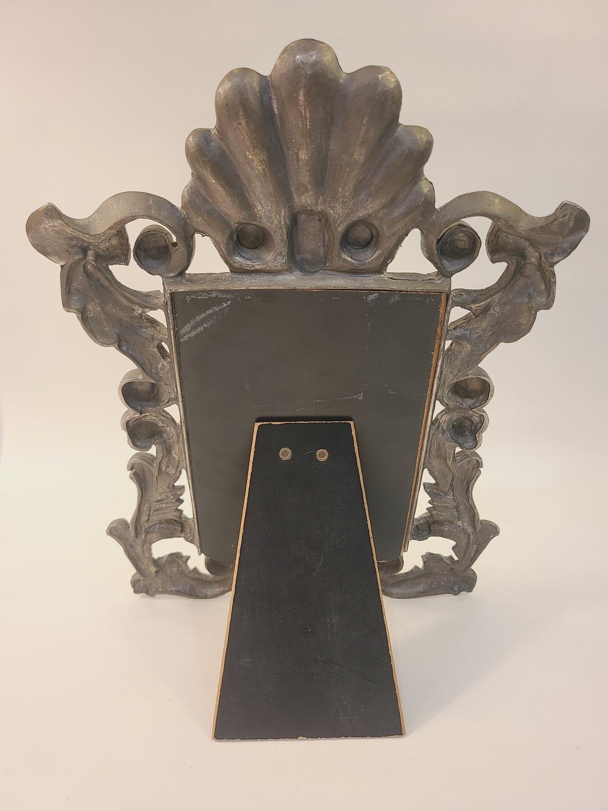 Back of Rococo Revival cast metal picture frame with fold-out easel stand extended, shell crest visible, vintage tabletop decor