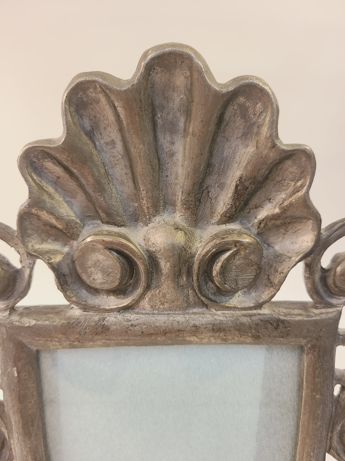 Close-up of cast metal shell crest on Rococo Revival picture frame with scroll details, antiqued bronze finish, coastal cottage decor