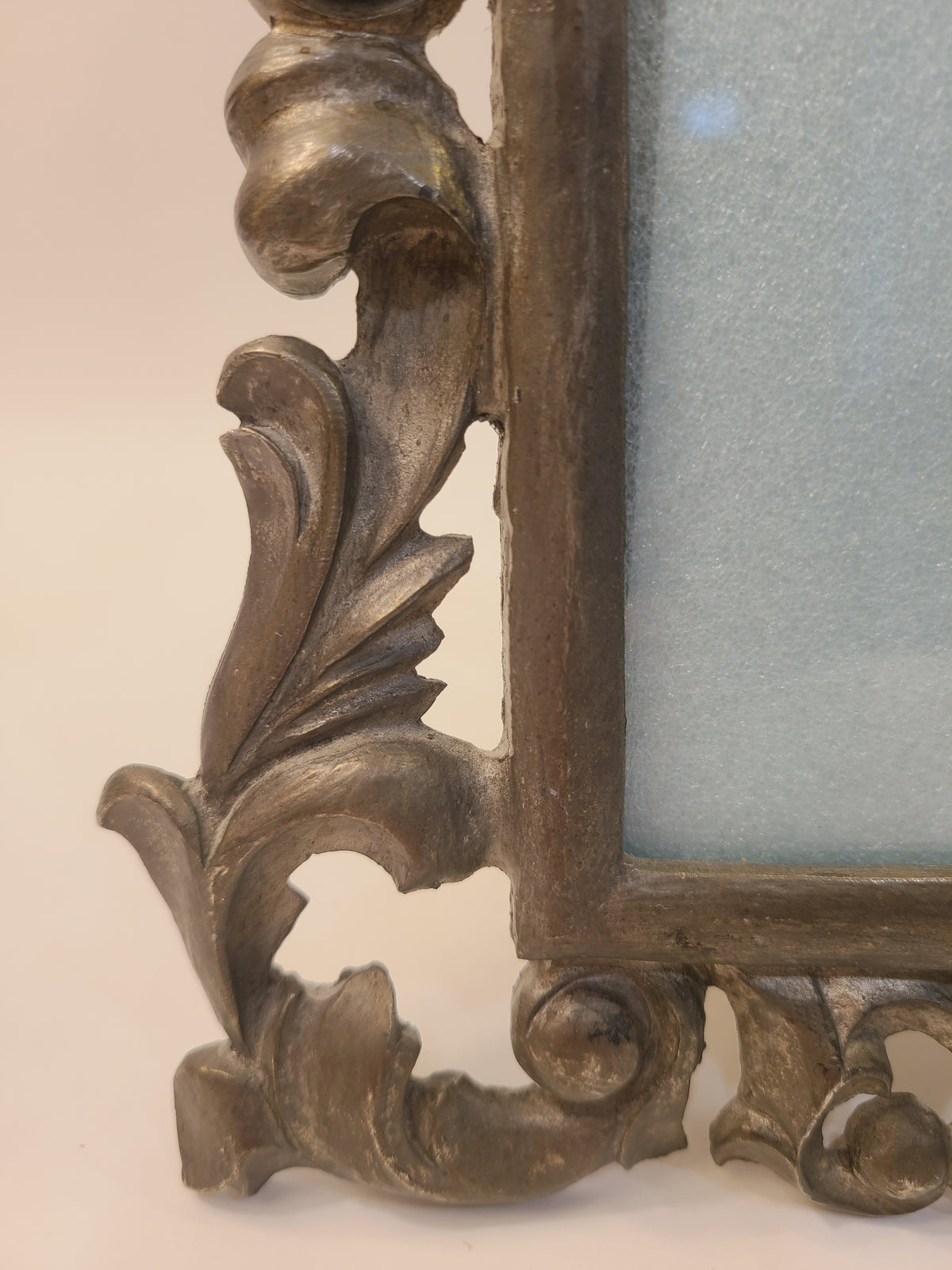 Close-up of lower corner acanthus leaf scrollwork on cast metal Rococo Revival tabletop frame, burnished antiqued bronze finish