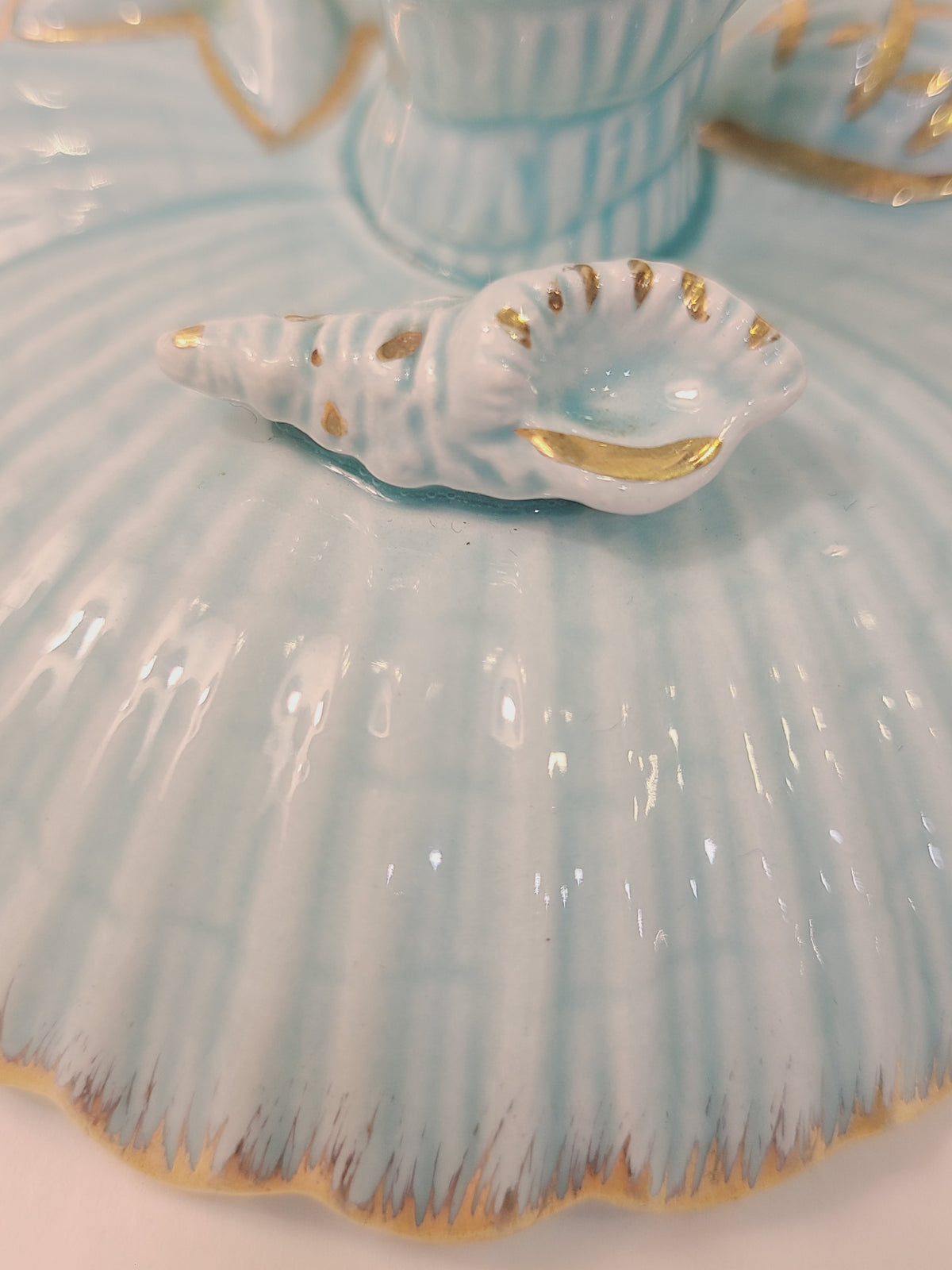 Close-up of gold-trimmed conch shell ceramic accent on 1962 NAPCO Tropic Sea aqua candle holder, mid-century coastal decor