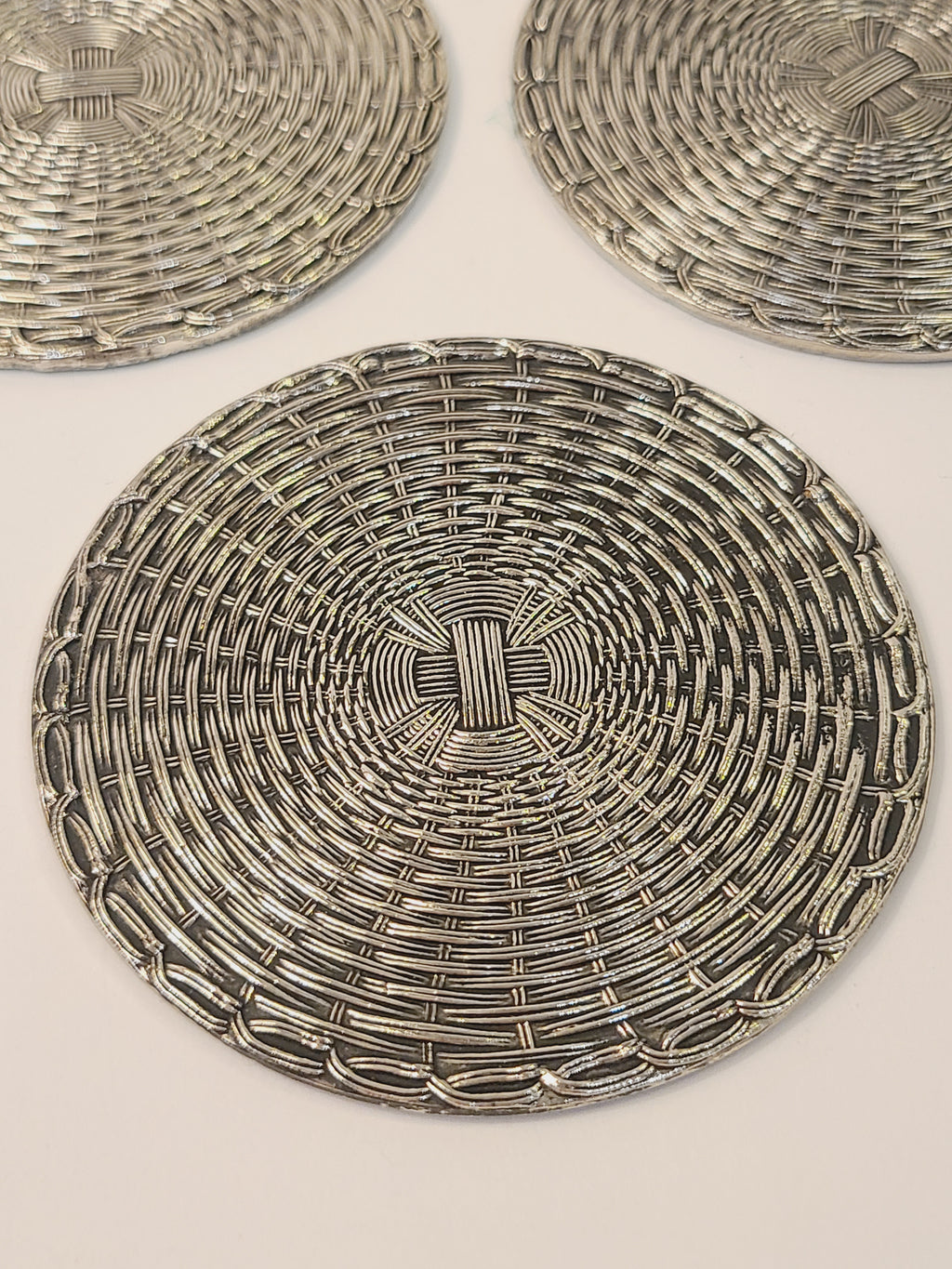 Fid-century European woven metal coasters top view showing circular basketweave pattern, polished silver with patina, circa 1950s–1970s