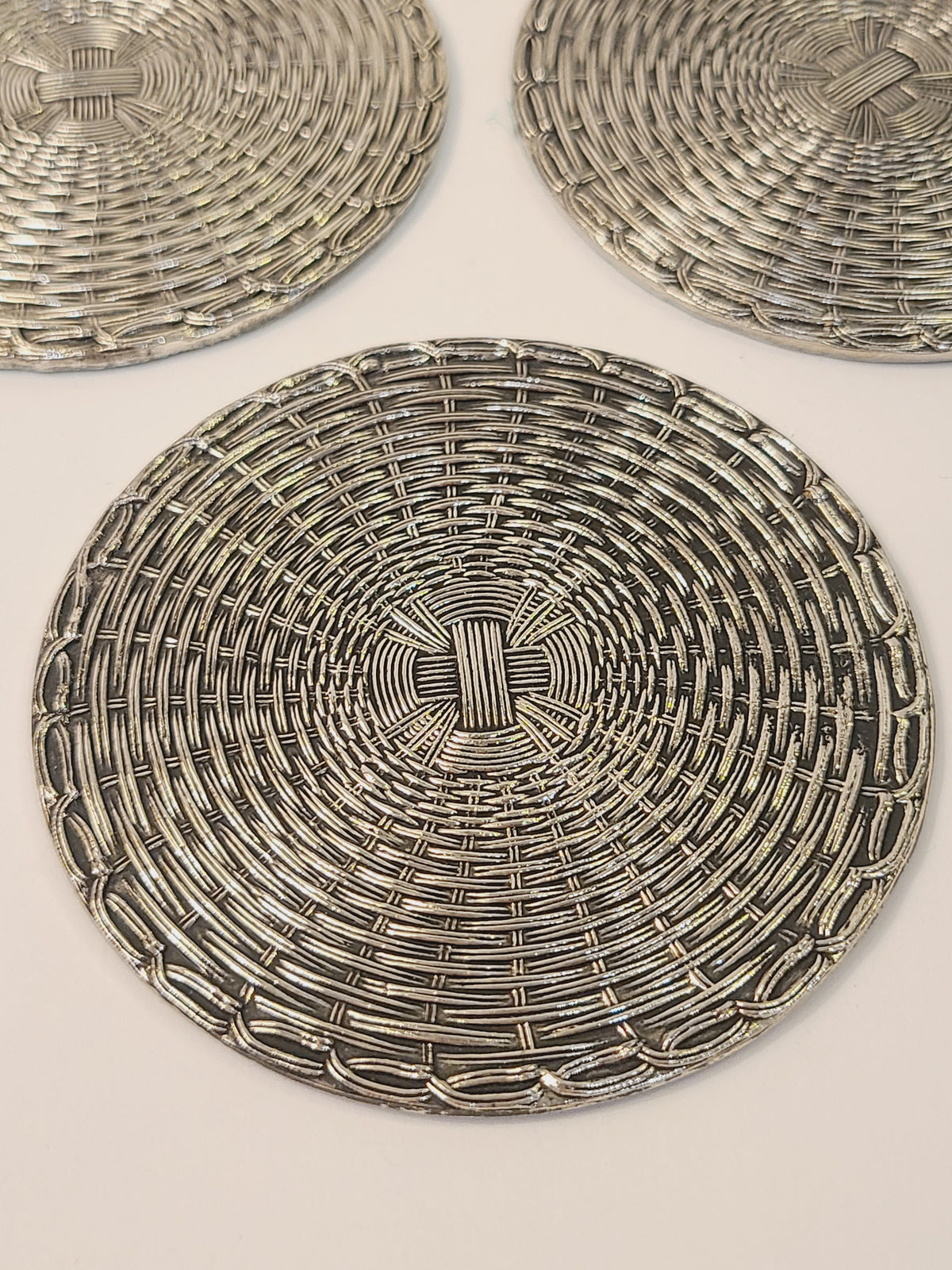 Fid-century European woven metal coasters top view showing circular basketweave pattern, polished silver with patina, circa 1950s–1970s