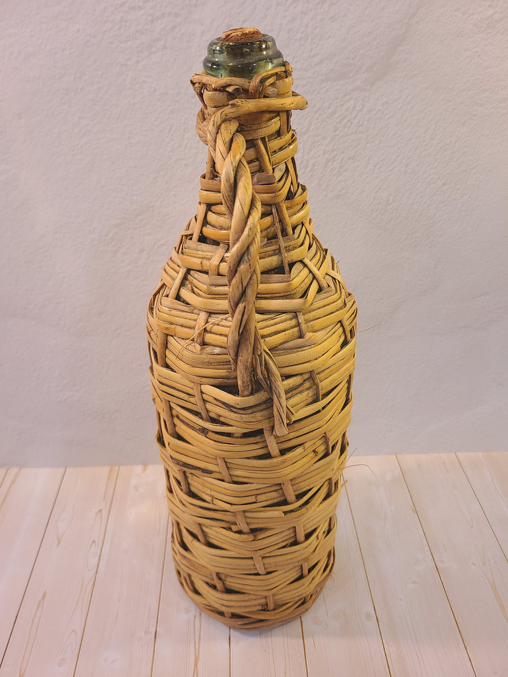 Side view of a vintage glass demijohn covered in natural woven rattan