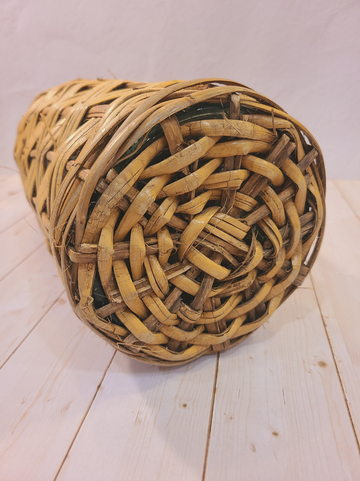 Bottom view of a vintage demijohn showing its tightly woven rattan-covered base