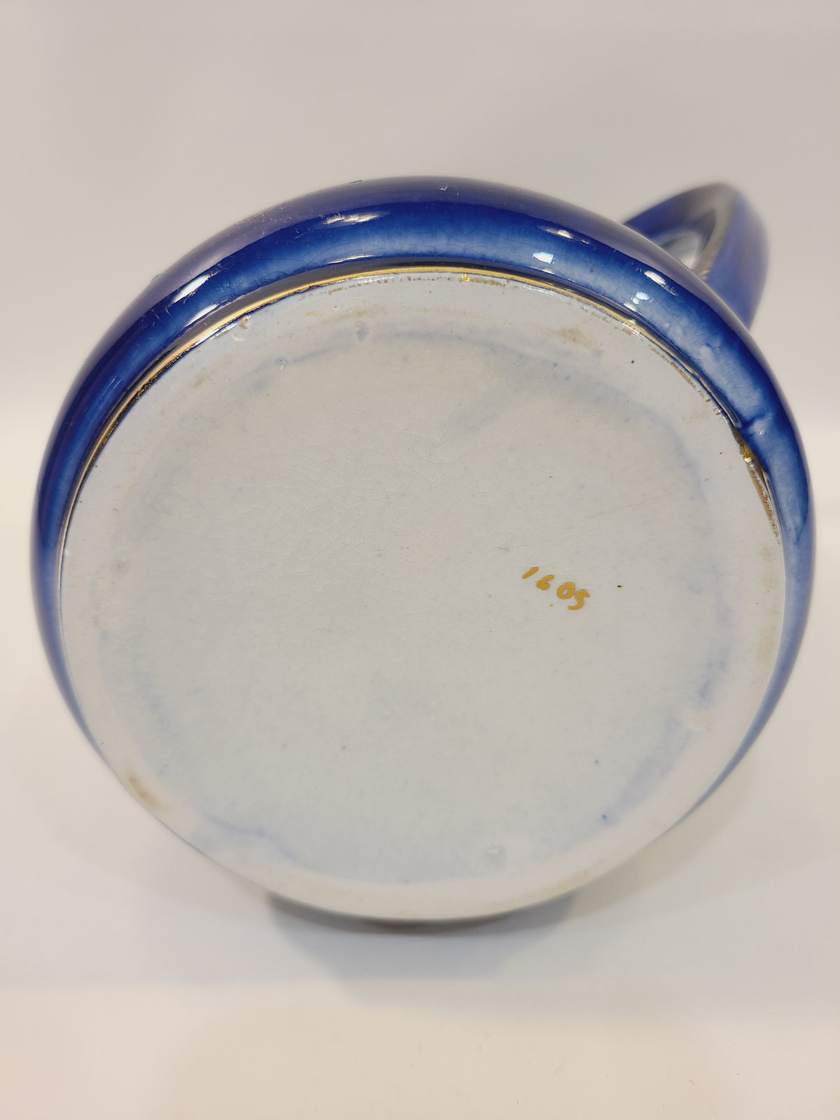 Underside of cobalt blue ceramic pitcher showing a handwritten pattern number and gold-trimmed base