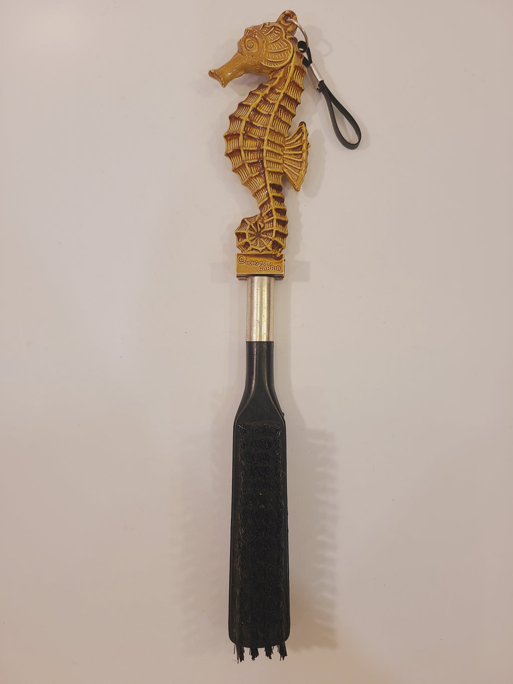 Vintage seahorse clothes and lint brush with tan sculptural handle, hanging loop, and black bristles