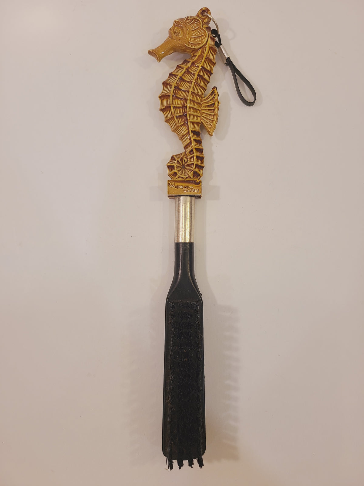Vintage seahorse clothes and lint brush with tan sculptural handle, hanging loop, and black bristles