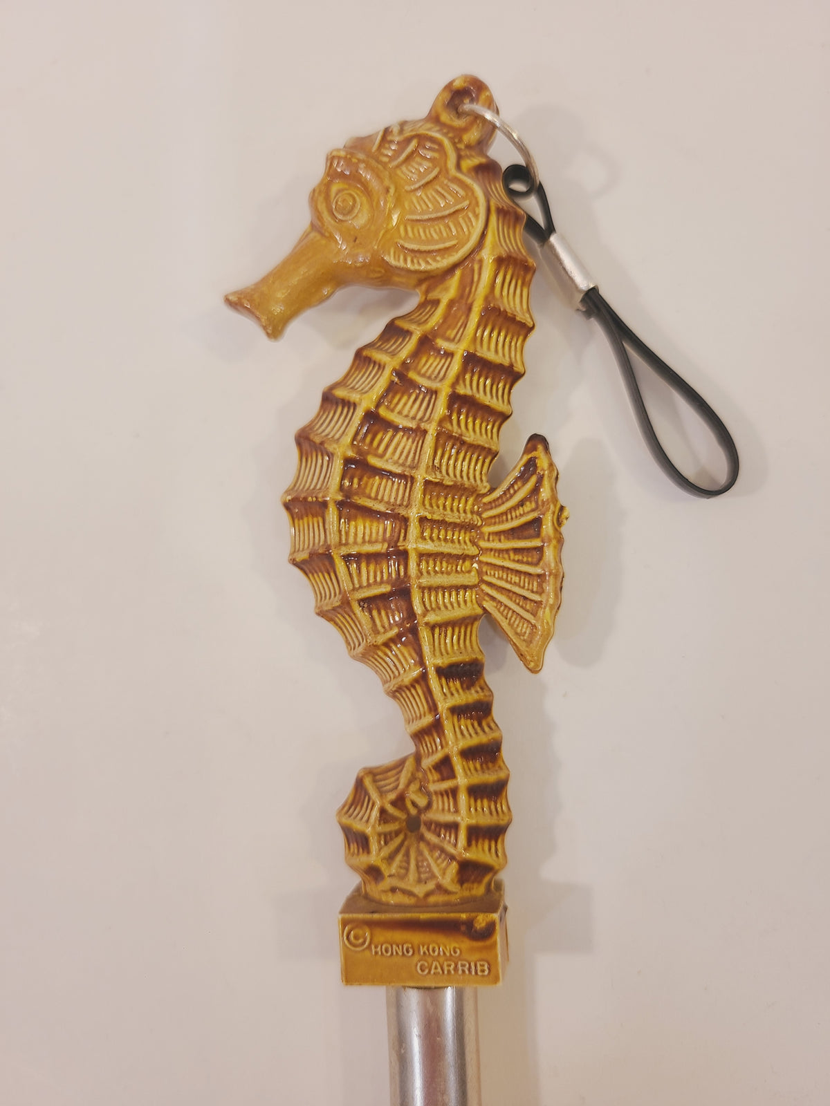 Vintage seahorse lint brush showing its sculpted body, ribbed details, and hanging loop along with Hong Kong Carrib maker's label
