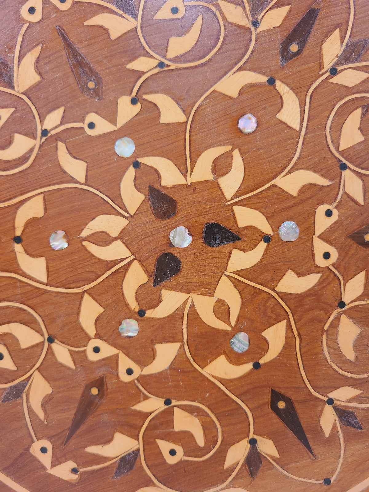 Close-up of botanical wood inlay and round mother-of-pearl accents on a vintage serving tray