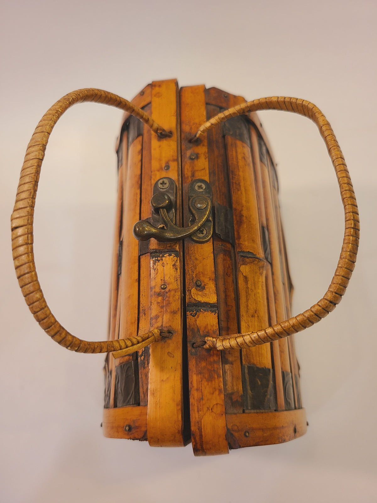 Closed vintage bamboo box handbag showing its woven handles, brass-tone latch, and structured trunk shape
