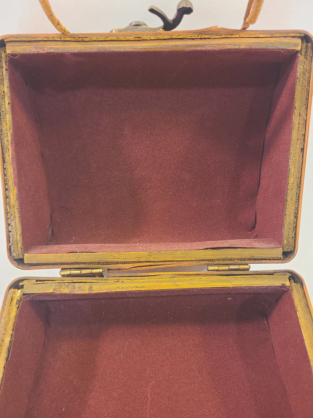 Close-up of burgundy velvet-like lining inside a vintage bamboo box handbag