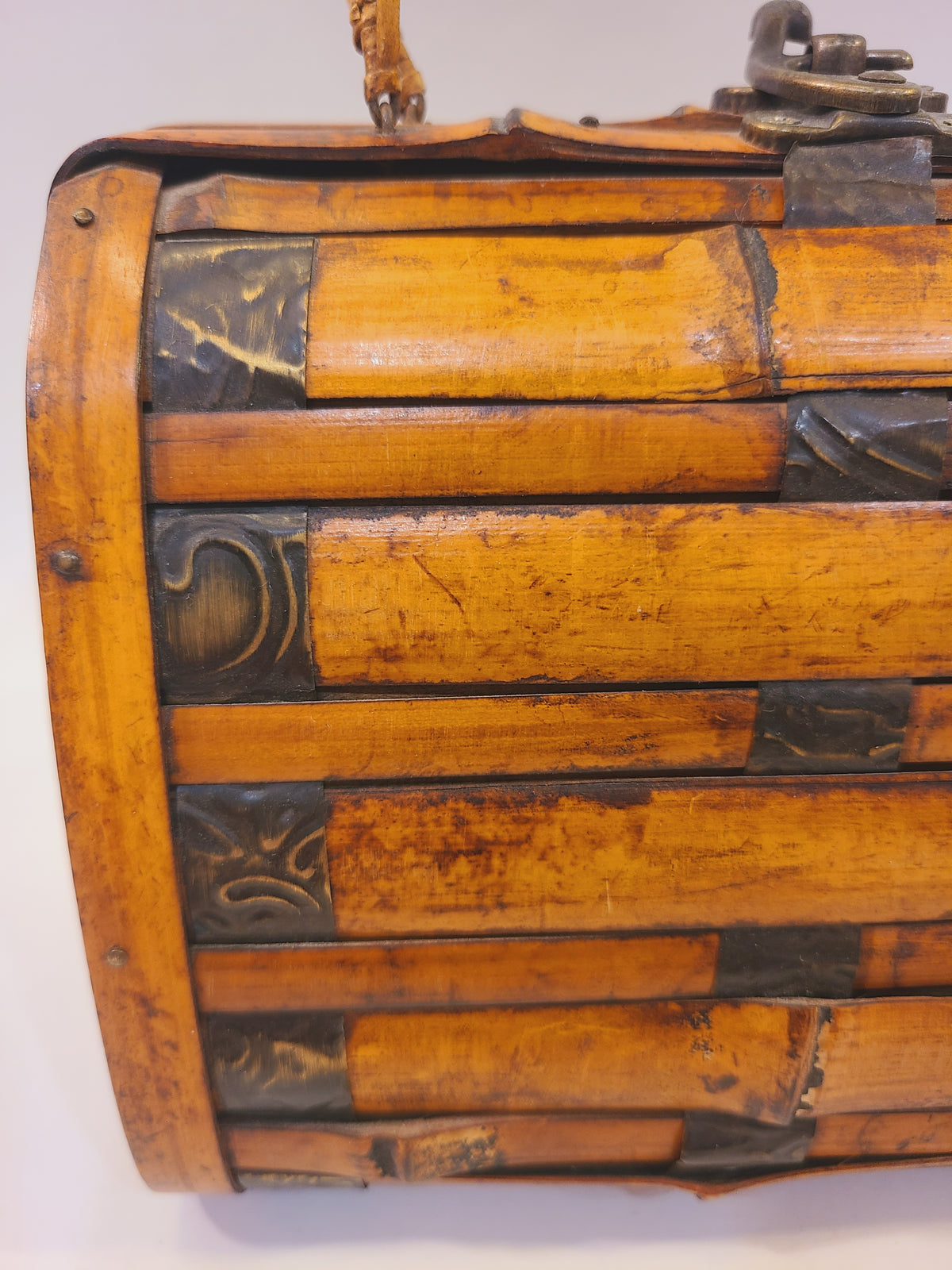Close-up of split bamboo slats, dark metal accents, and warm amber wood finish on a vintage handbag