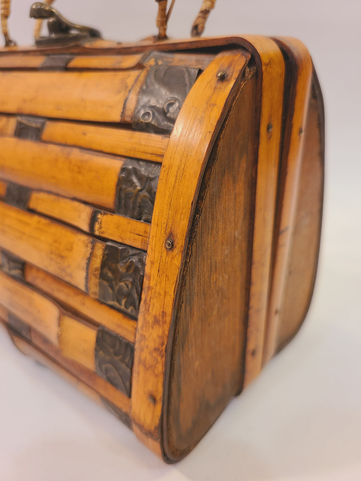 Close-up of wood framing, brass hardware, and decorative metal accents of vintage bamboo trunk box handbag
