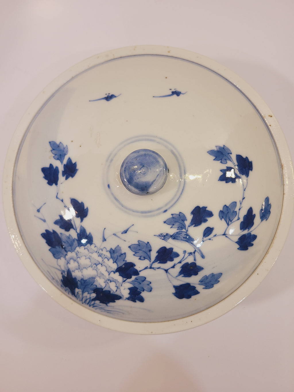 Top view of the domed porcelain bowl lid with cobalt blue floral and bird decoration and round knob. East Asian