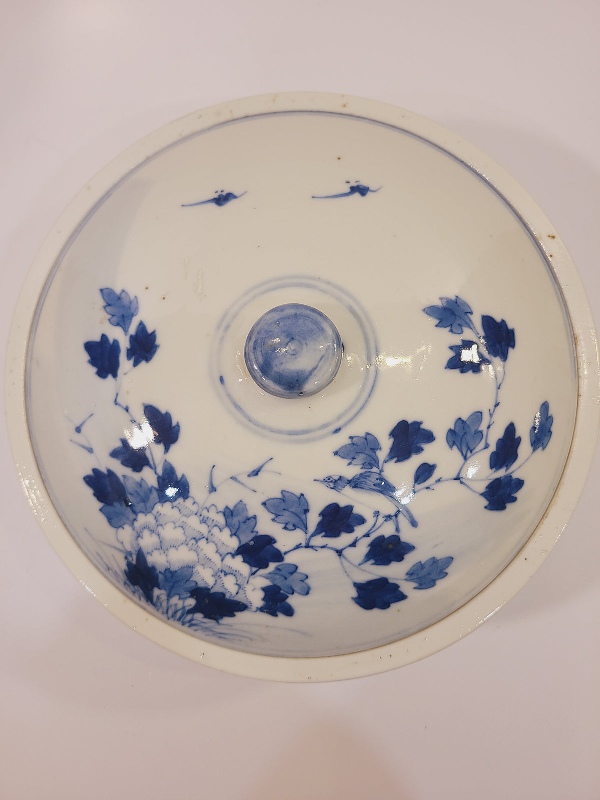Top view of the domed porcelain bowl lid with cobalt blue floral and bird decoration and round knob. East Asian