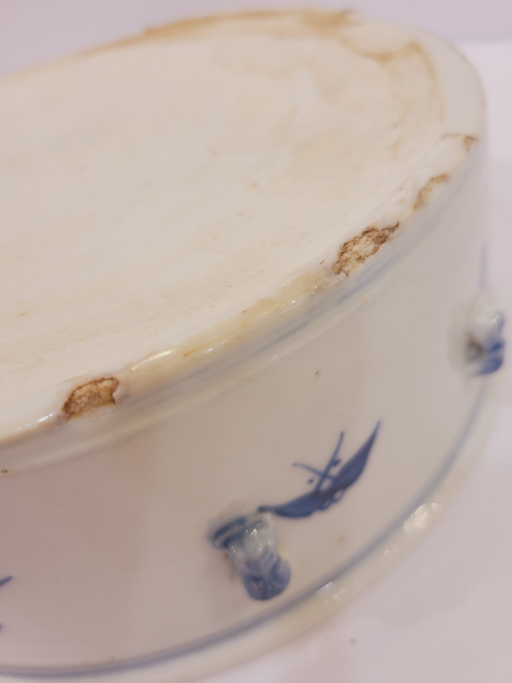 Detailed view of edge chips and age-related wear on the blue and white porcelain bowl